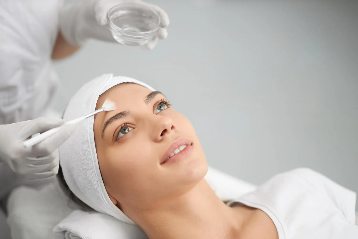 Esthetician brushing a chemical peel onto a woman's face