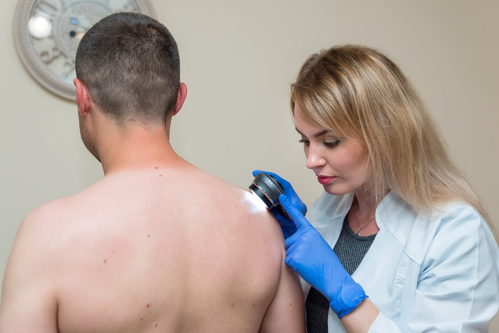 Dermatologist examining a man's shoulder with a dermatoscope
