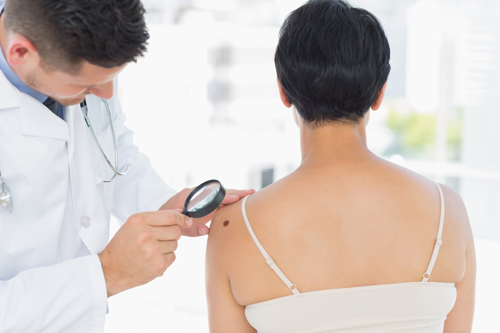 Doctor in a white coat examining a patient's upper back with a magnifier
