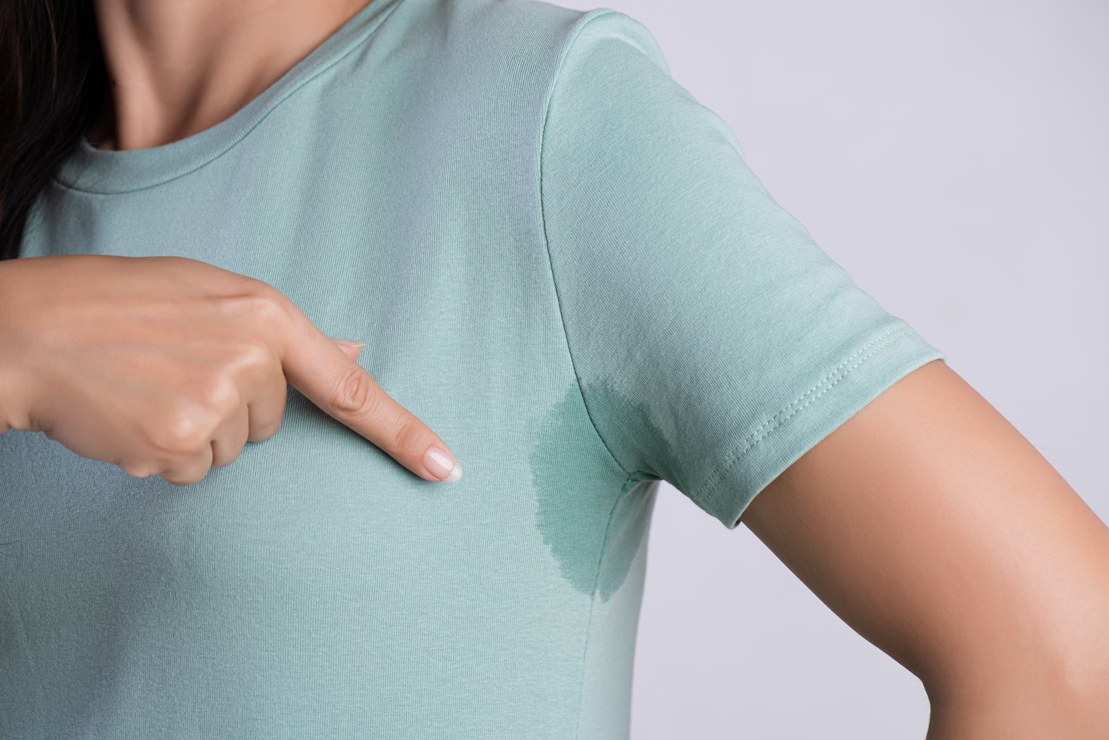 Woman pointing at a sweat mark under the arm of her green top