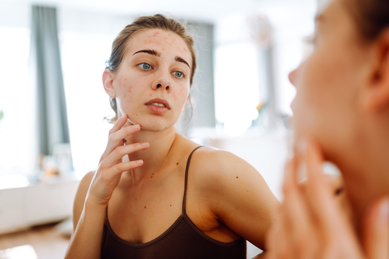 Woman looking at the skin on her face in a mirror