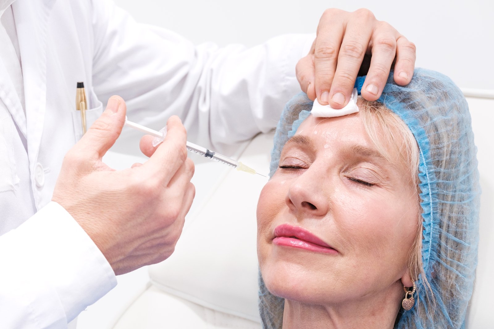 Clinician holding a syringe to a patient's forehead in a treatment room