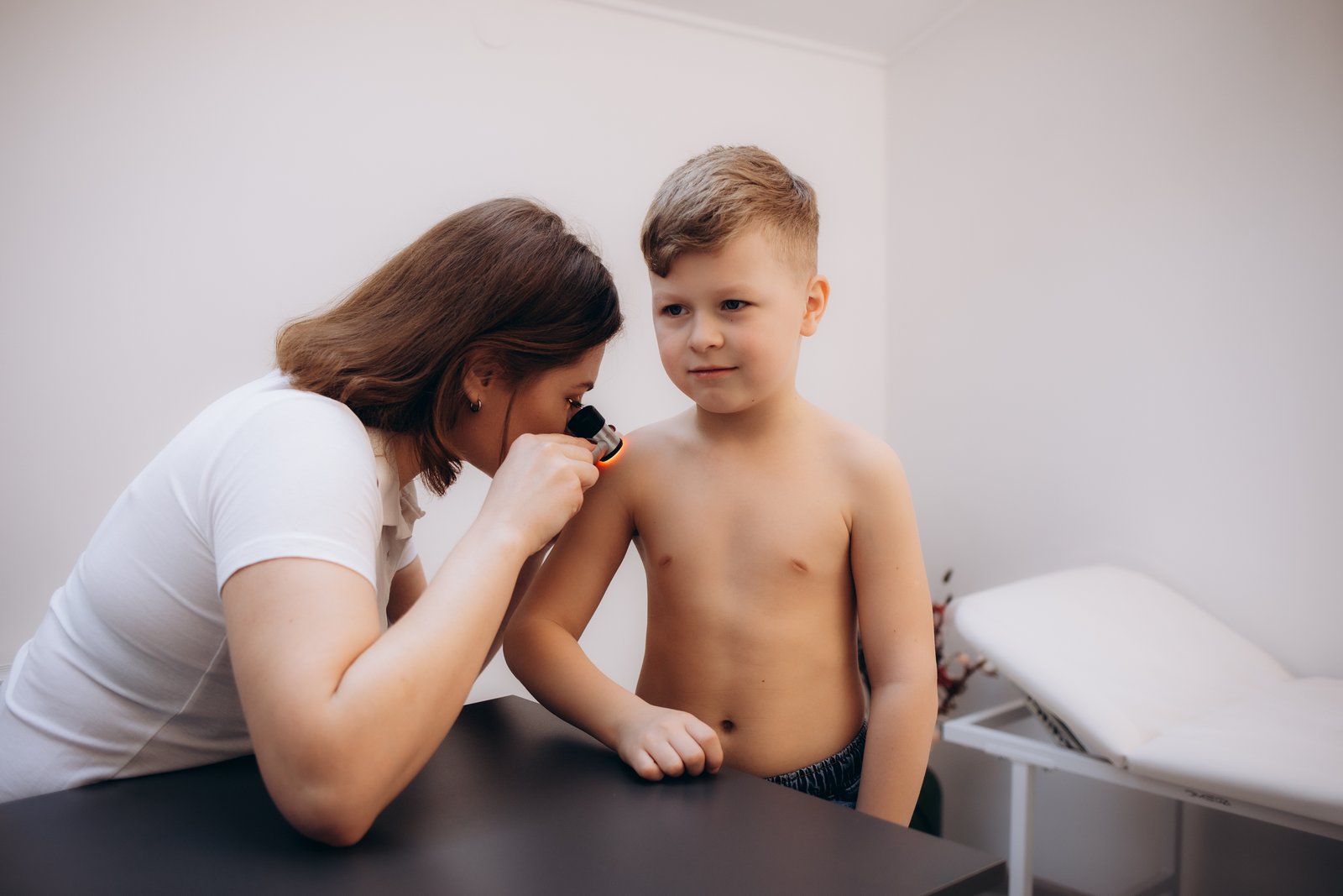 Clinician holding a dermatoscope to a spot on a child's shoulder