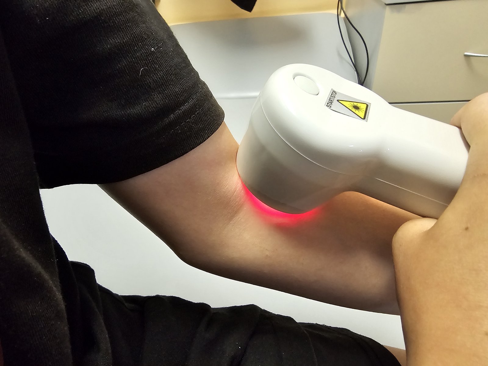 Handheld light therapy device held against a patient's bent elbow